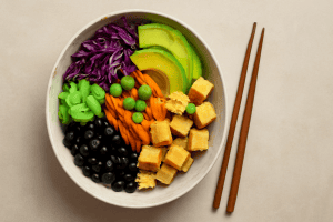 Vegan poke bowl with fresh vegetables like purple cabbage, avocado, carrots, edamame, tofu cubes, and black seaweed, ideal for those seeking fish-free alternatives.